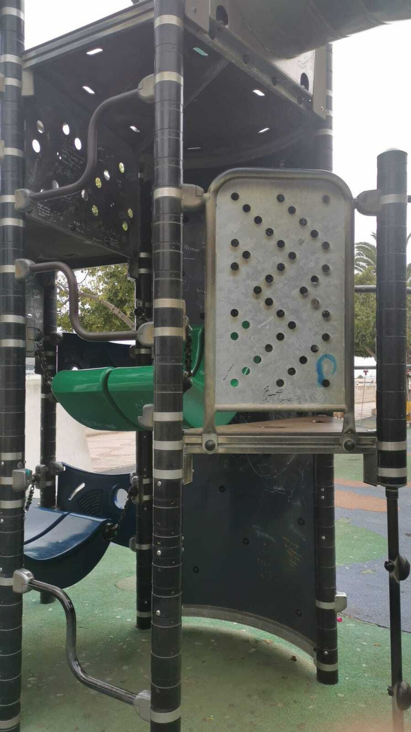 La niña introdujo la pierna entre la columna negra y la placa metálica.