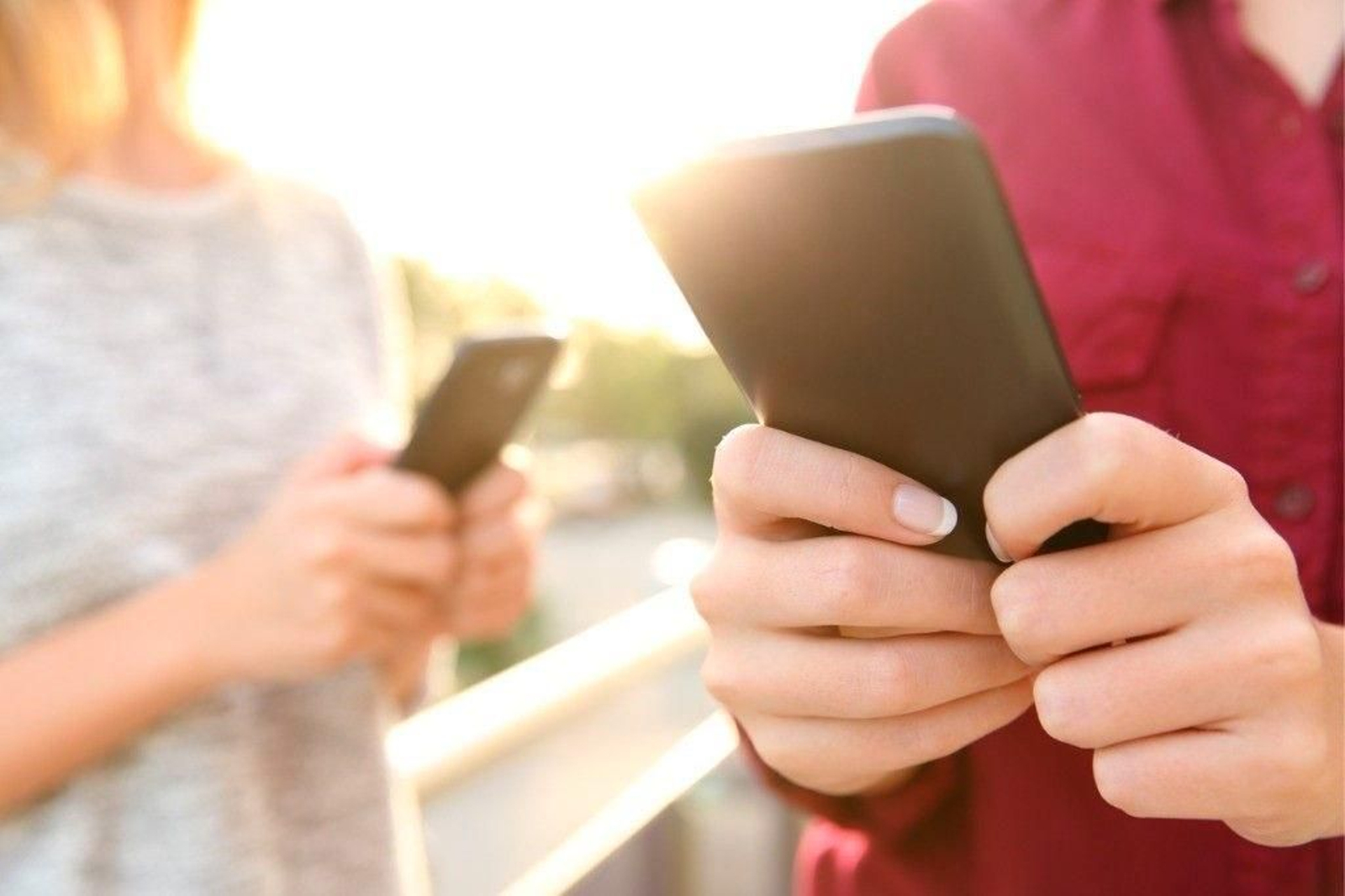 Dos menores de edad usando sus teléfonos móviles en una imagen de archivo