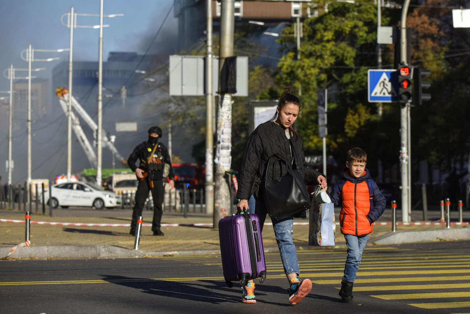 Una mujer con un niño cruza una calle tras un ataque con drones en Kiev.