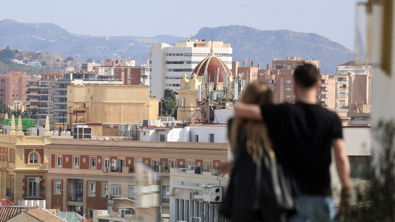 Una pareja divisa viviendas del centro histórico de Málaga.