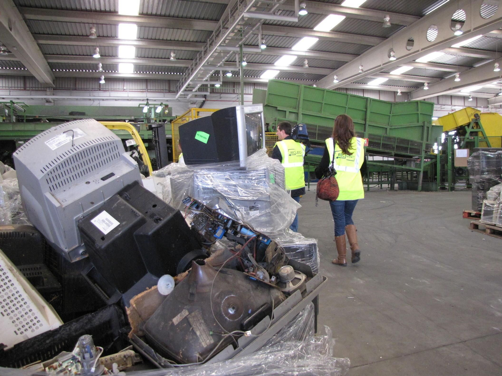 Montaña de televisores y monitores con tubos de rayos catódicos en una planta de reciclaje.