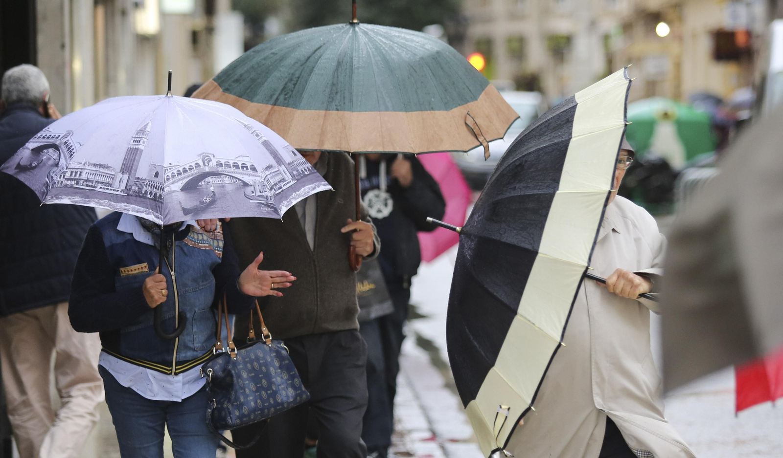 Varias personas parapetadas bajo sus paraguas en Málaga capital.