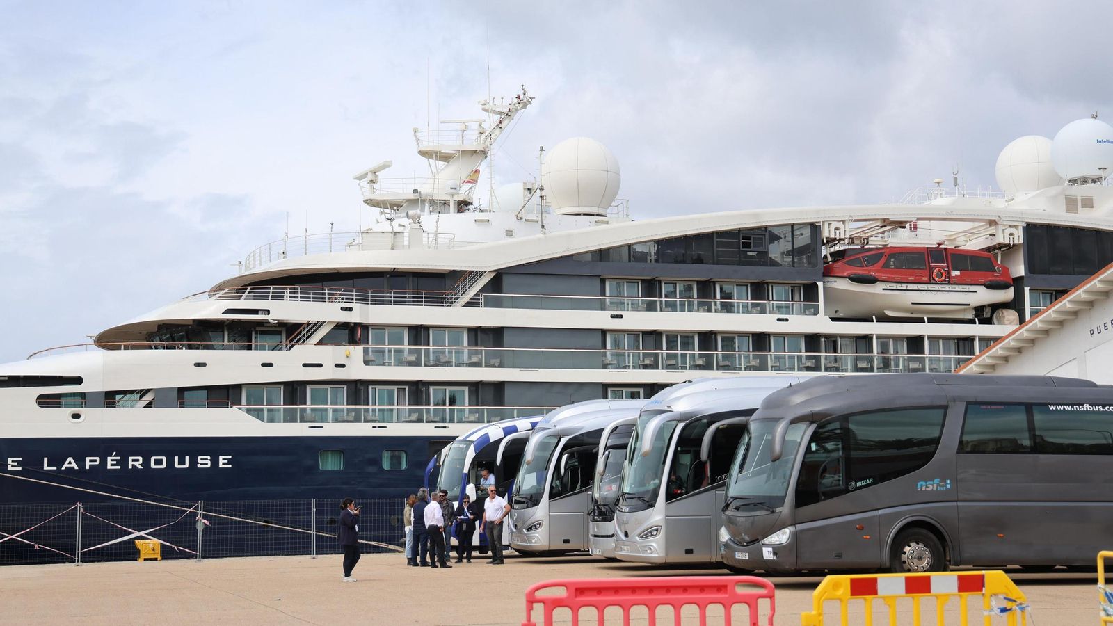 Autobuses junto al buque de lujo que hace escala en Huelva, este jueves.