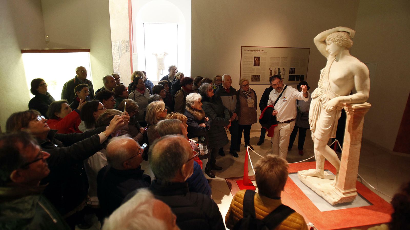 Un grupo de turistas observa la Amazona Herida en el Palacio de Benamejí.