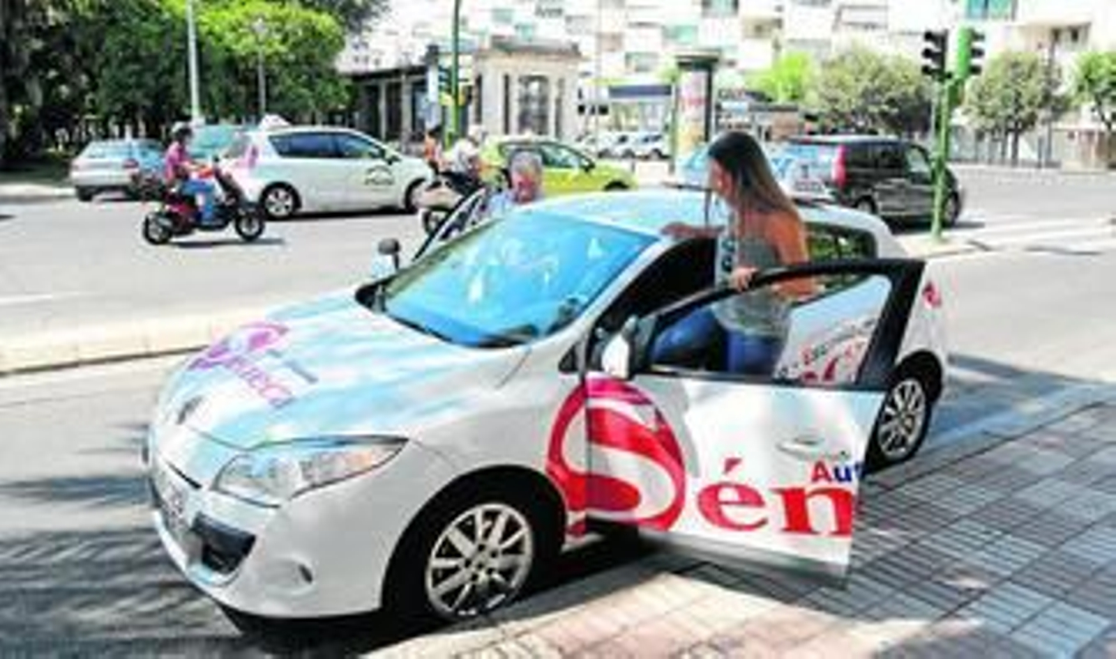 Una alumna se monta en un coche de una autoescuela de Córdoba para recibir una clase práctica.