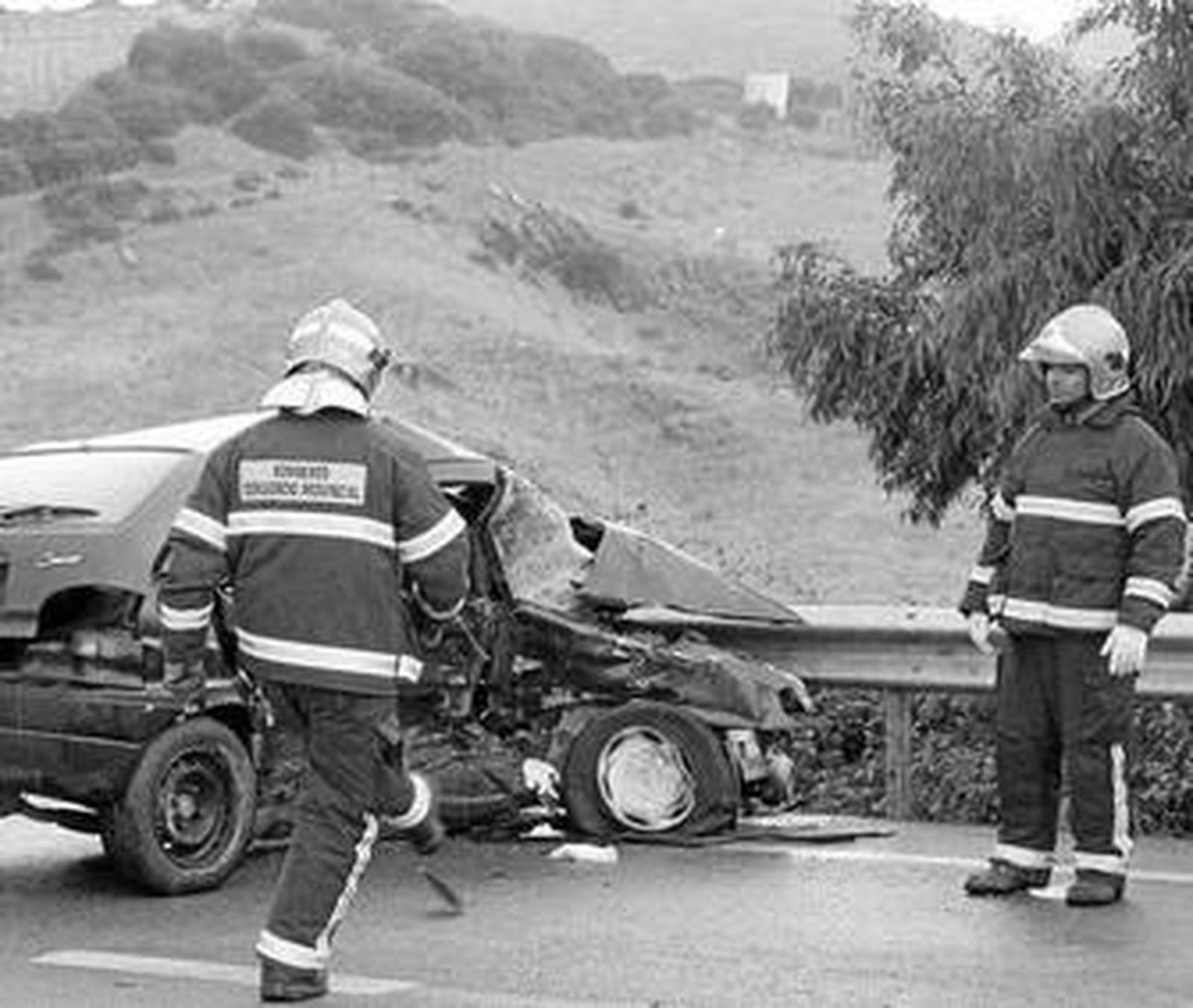 Dos bomberos observan el estado del automóvil en el que viajaba el fallecido, ayer.