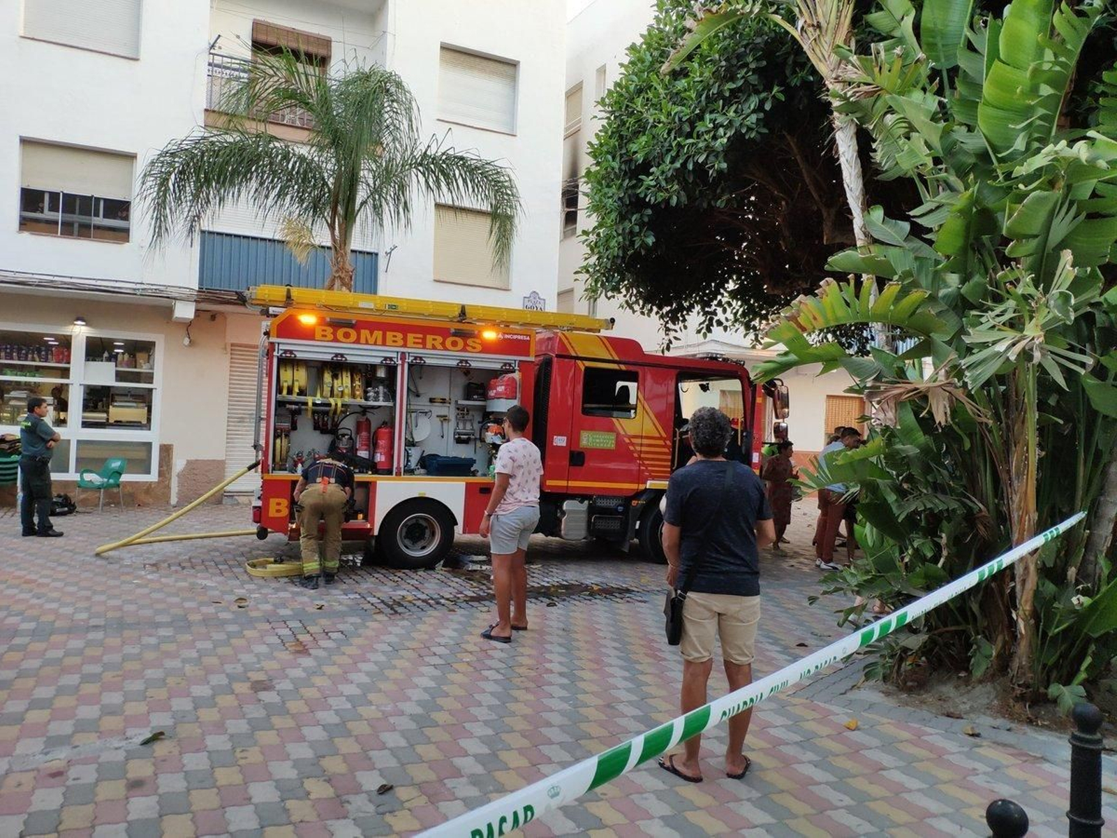 Bomberos y vecinos observan el bloque incendiado.