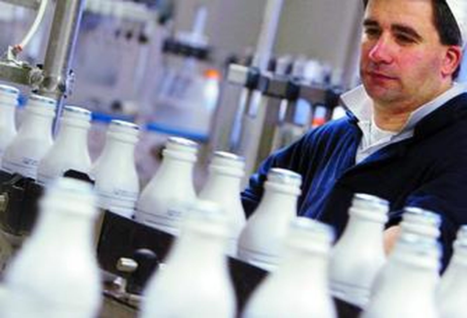 Un operario vigila la producción en una planta de embasado y distribución de leche.