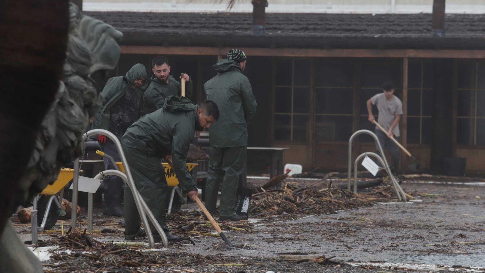 Un grupo de personas limpia en uno de los chiringuitos de Sotogrande arrasados por el agua.