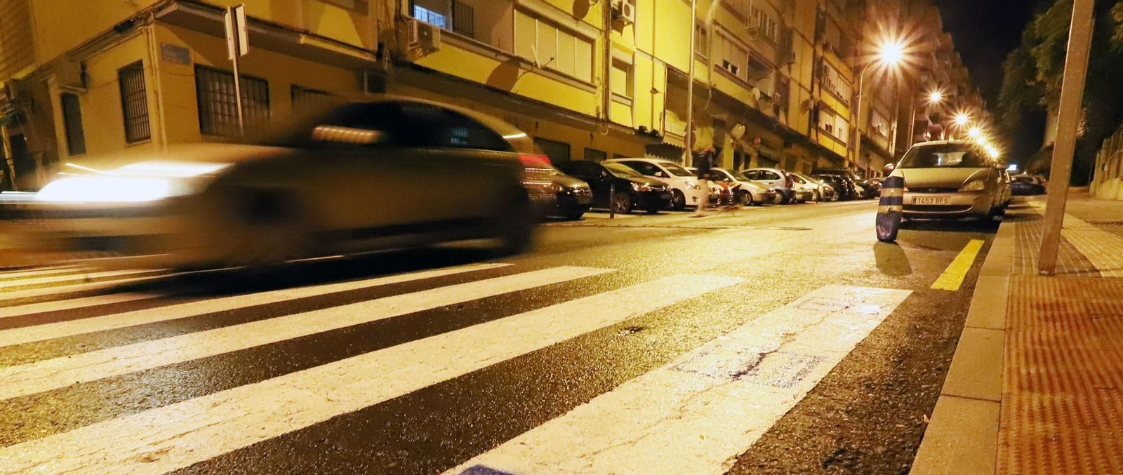 Un coche pasa por un paso de peatones en Huelva por la noche.