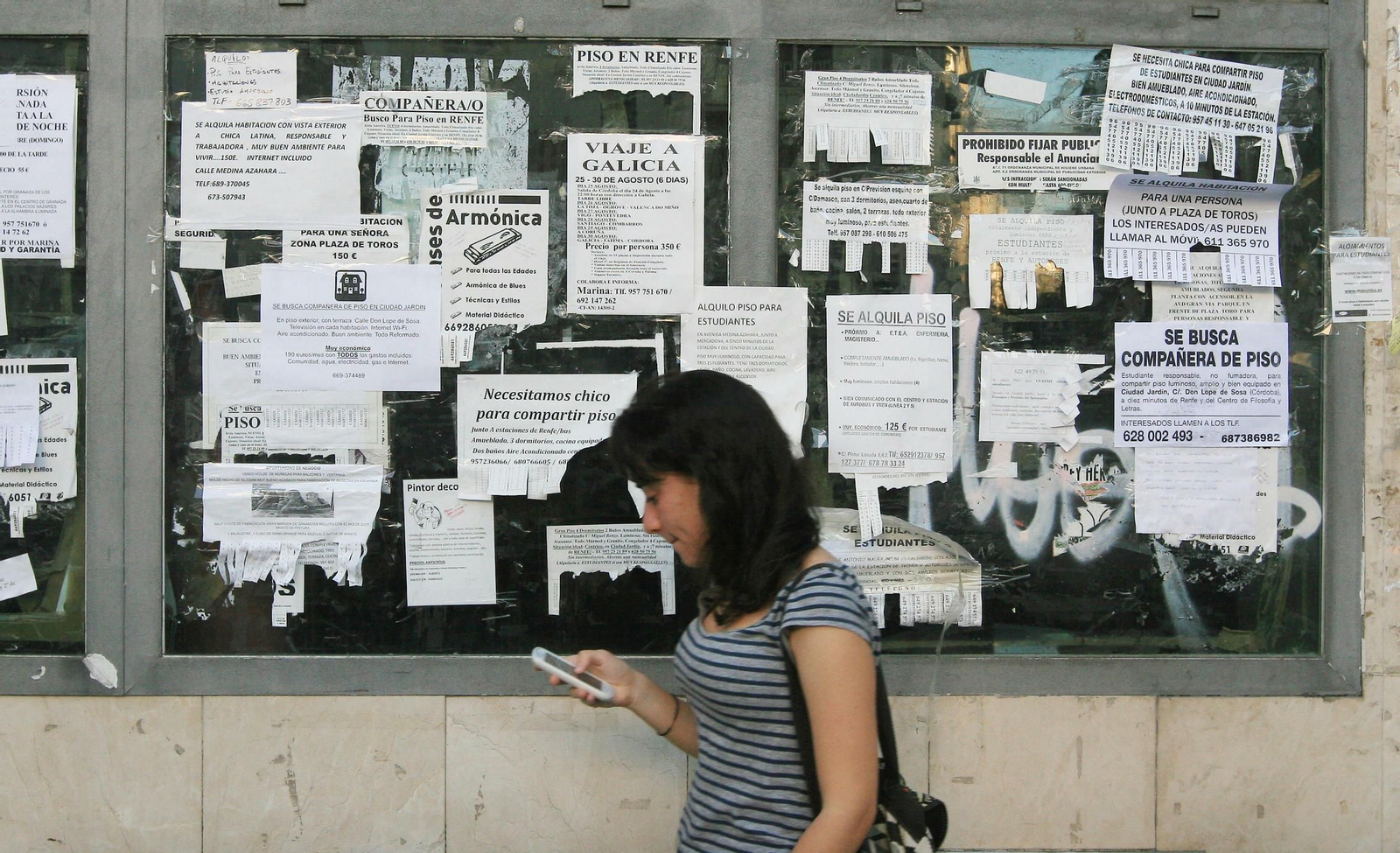 Una mujer pasa cerca de carteles de alquiler.