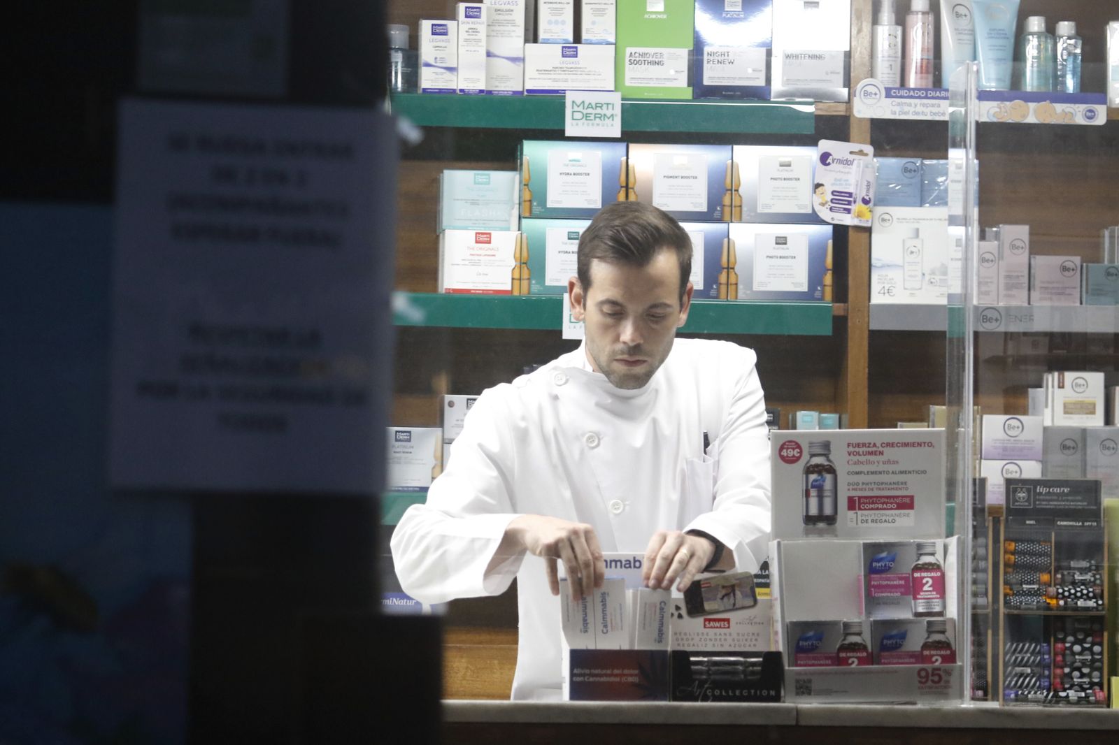 Un profesional de farmacia coloca los productos del mostrador.