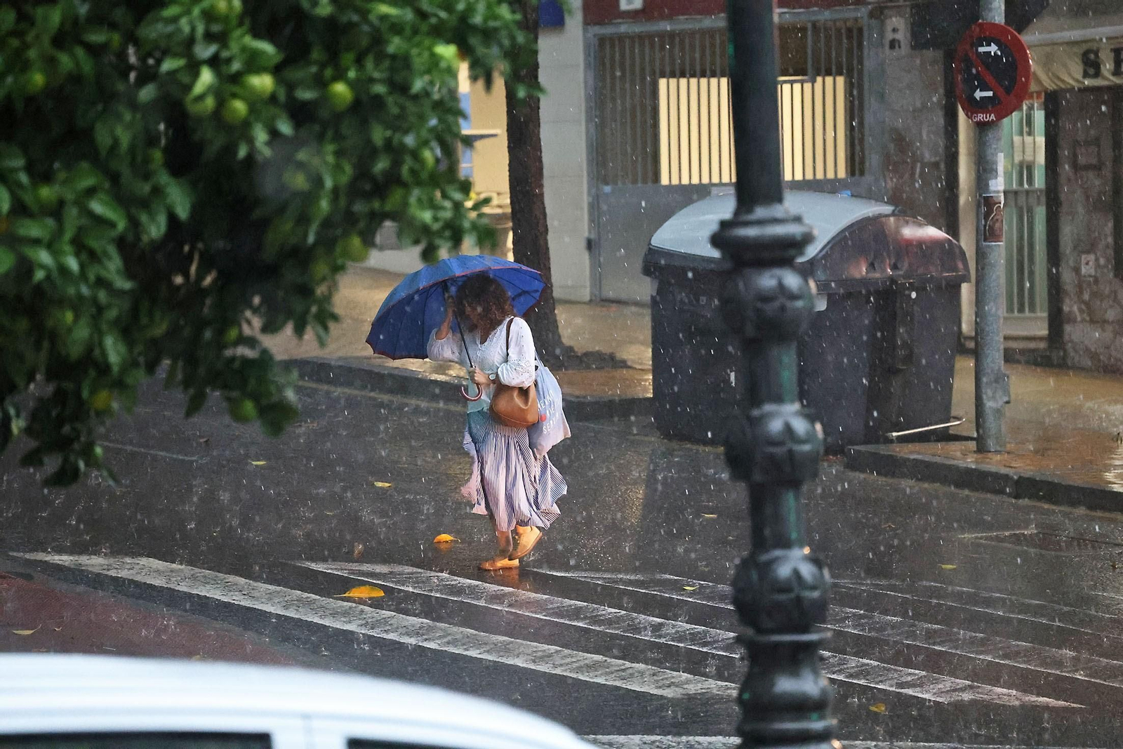 Una mujer se resguarda de la intensa lluvia en Huelva.
