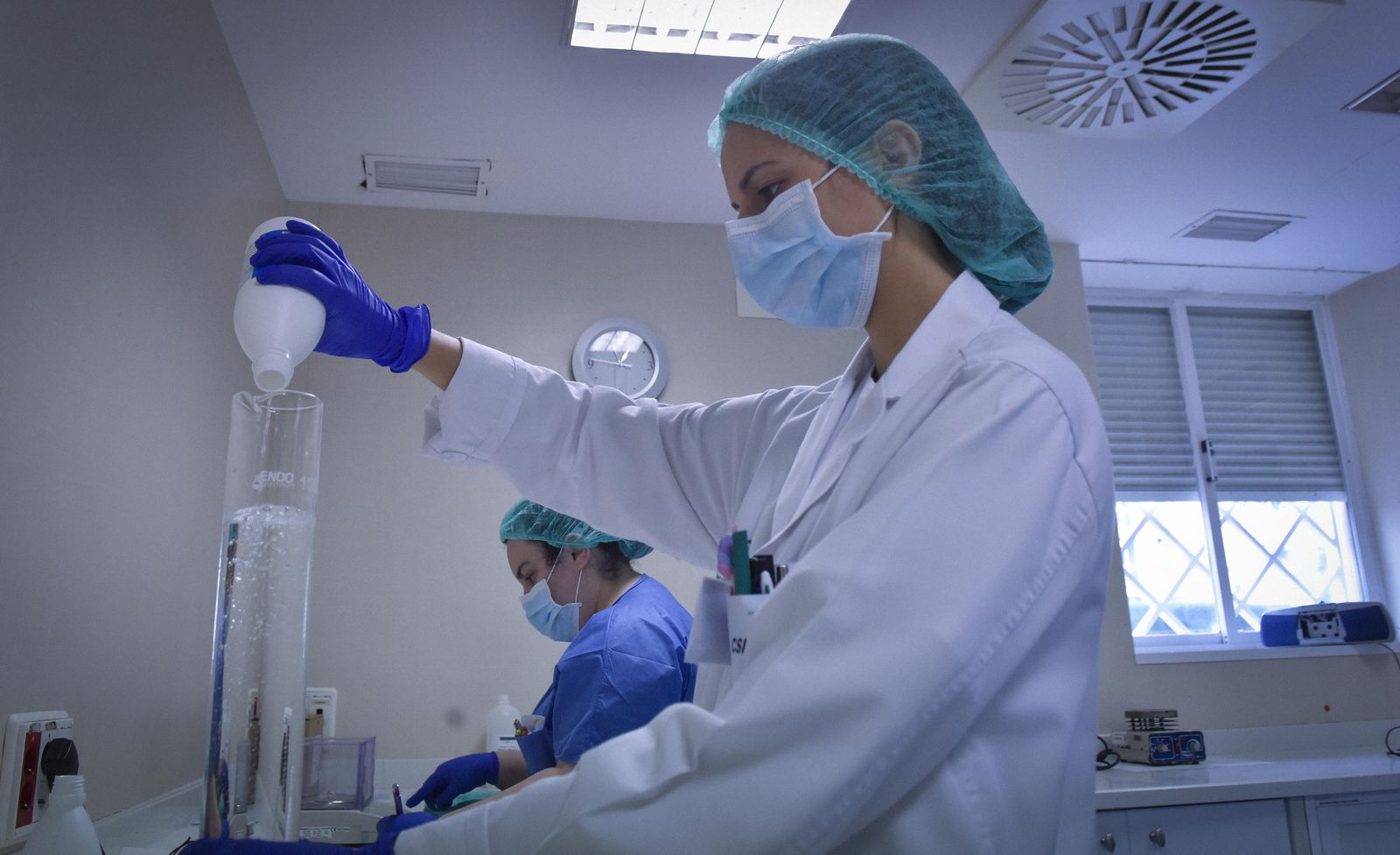 Una sanitaria sostiene dos recipientes con solutos en el laboratorio del Hospital Virgen del Rocío de Sevilla.