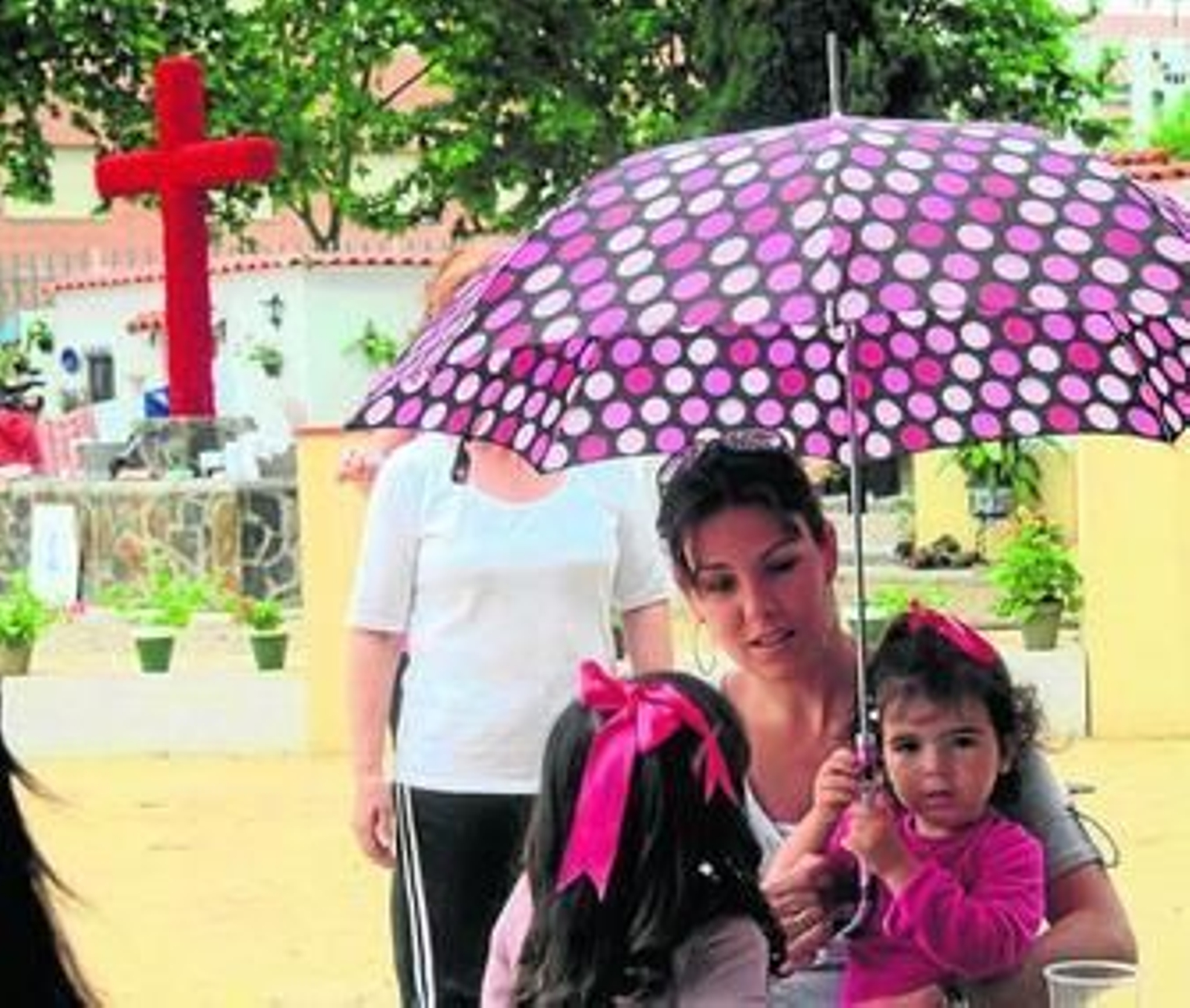 Una joven se cobija junto a sus pequeñas debajo de un paraguas.