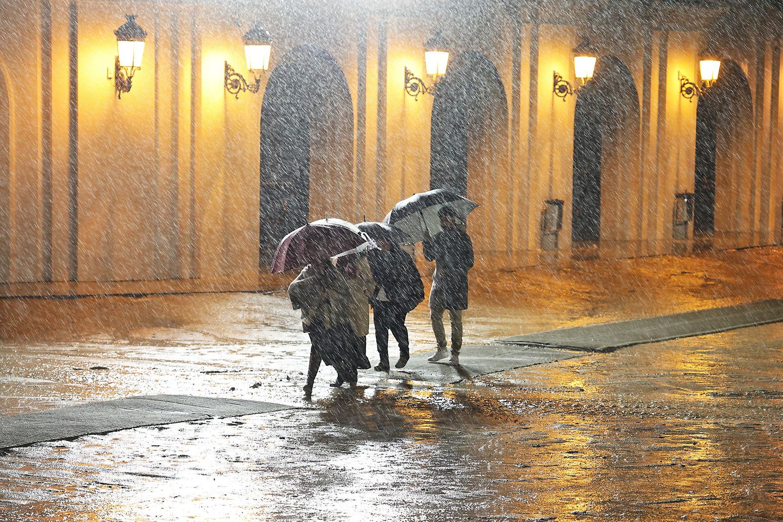 Varias pesronas se refugian de la lluvia con paraguas.