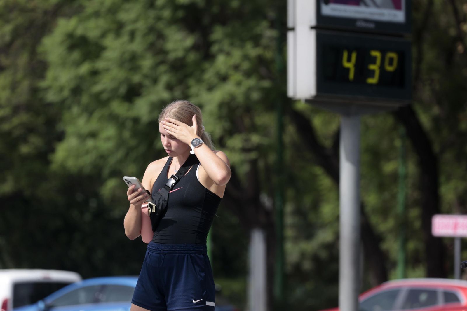 Una mujer se cubre la frente mientras un termómetro marca 43 grados