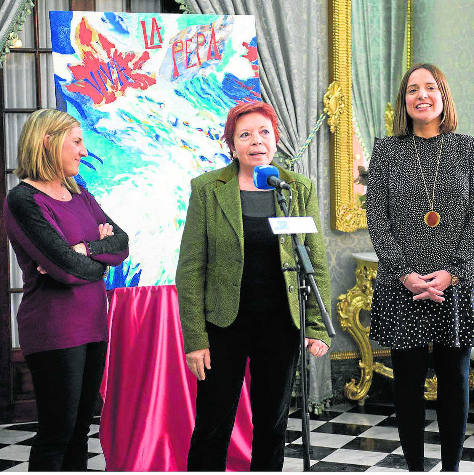 Candi Gabarino, delante de su obra, acompañada por Irene García y Ana Carrera.