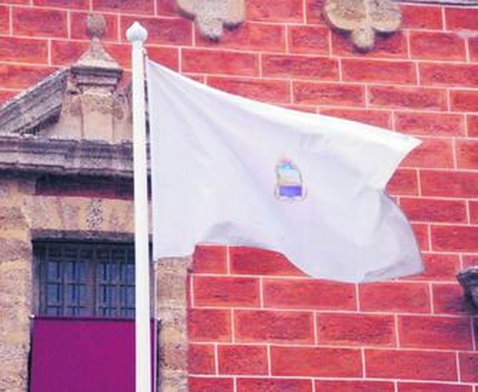 La ya antigua bandera blanca de San Fernando, en una imagen de ayer, en la plaza de la Iglesia.