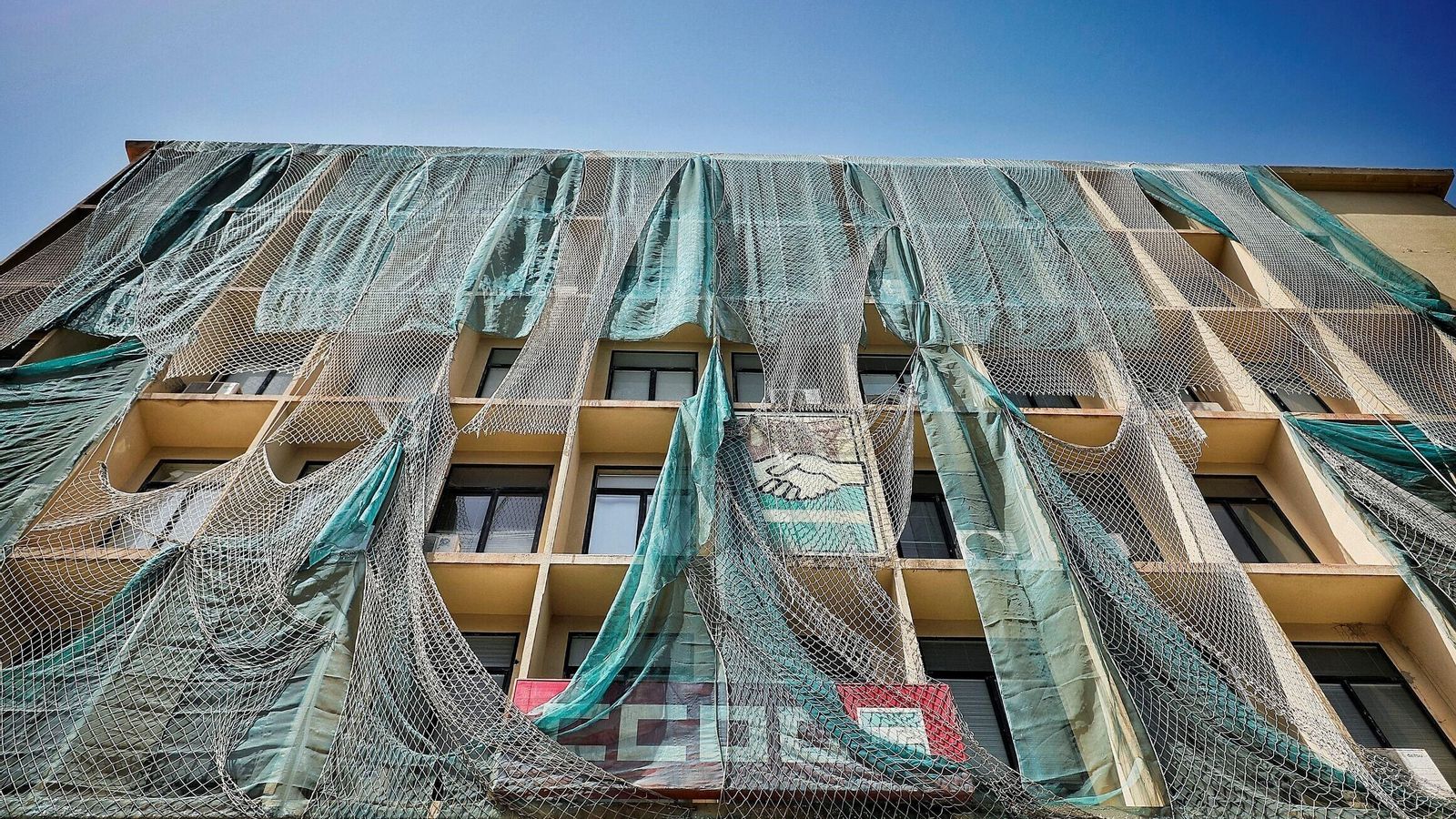 La red protege a los peatones de las continuas caídas de cascotes desde la fachada del edificio de los sindicatos de Cádiz