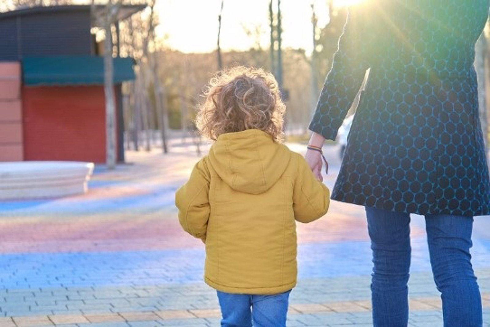Una madre pasea con su hijo de la mano.