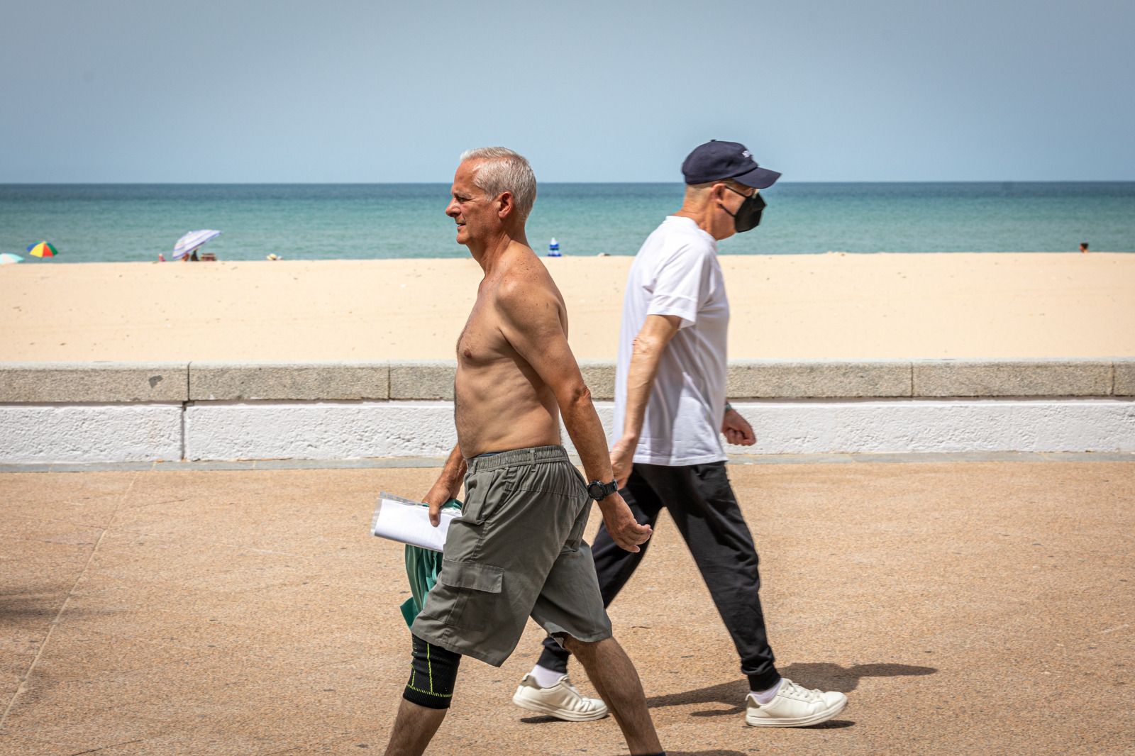 Dos personas pasean por el Paseo Marítimo de Cádiz en un día de altas temperaturas.