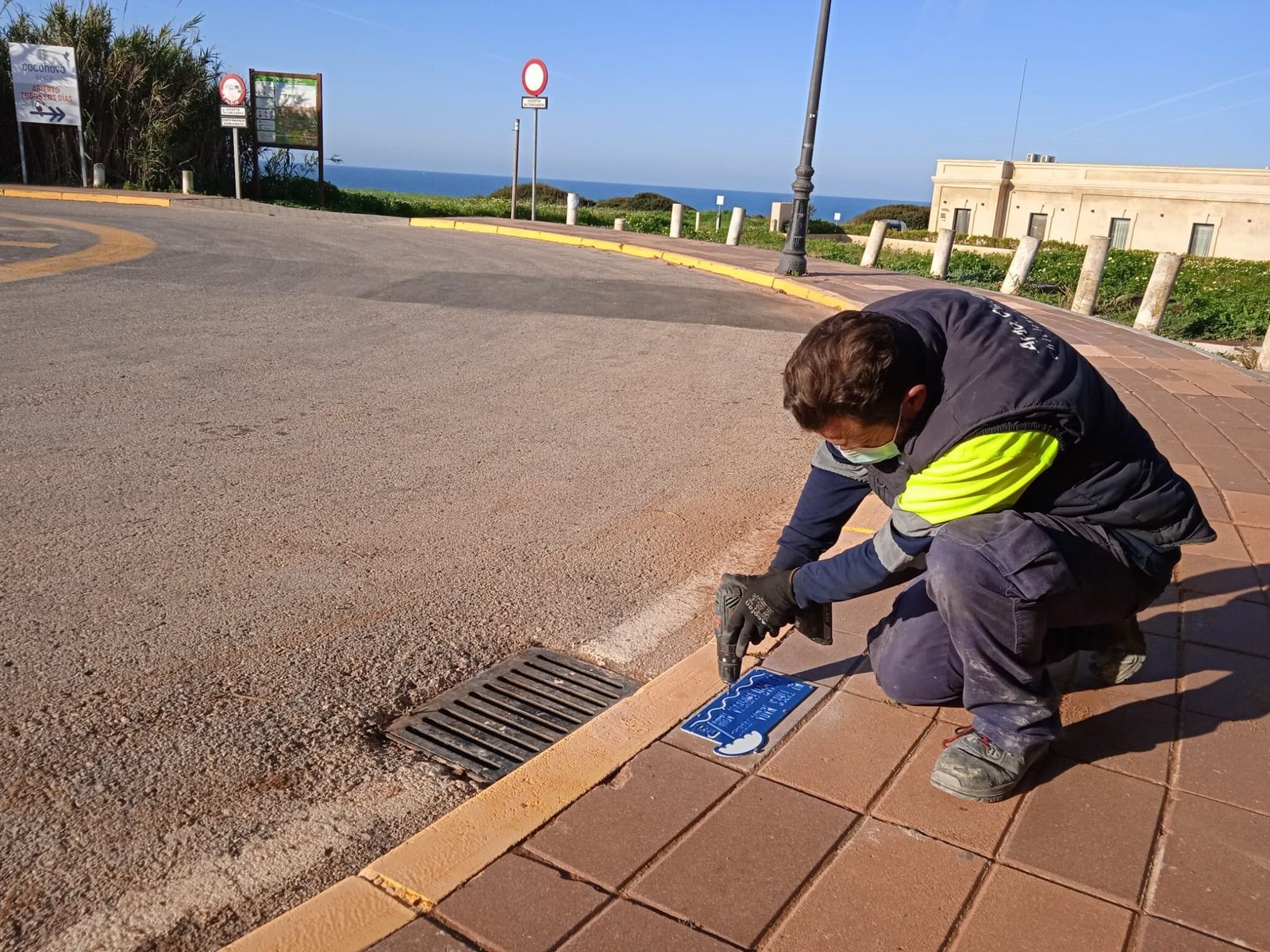 Un operario coloca una de las placas en los imbornales de pluviales con la inscripción ‘No tires nada. El mar empieza aquí’.