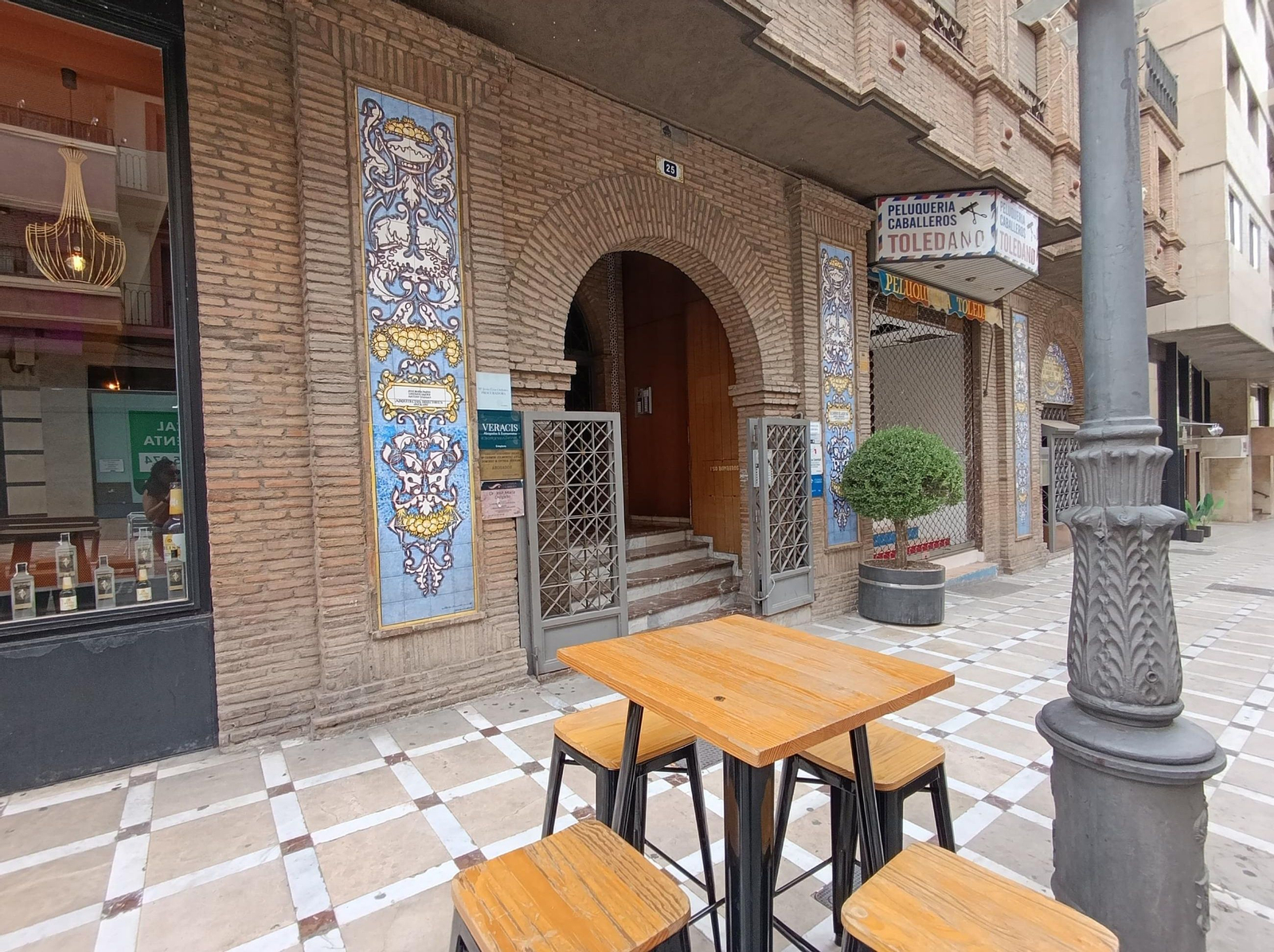 La portada de la Real Sociedad Económica 'Amigos del País' junto a una de las terrazas que pueblan la calle Bernabé Soriano.