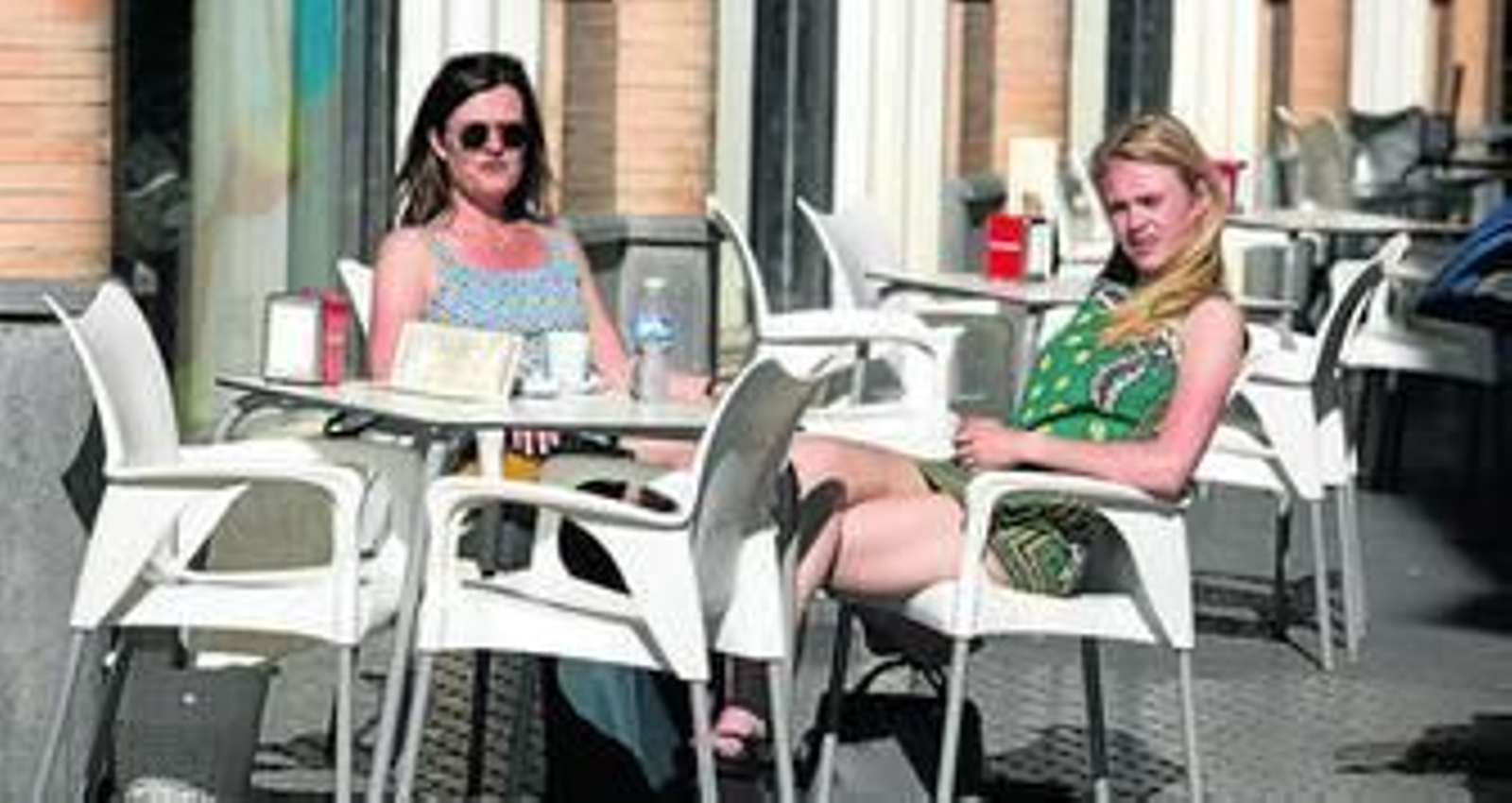 Dos mujeres descansan mientras toman un refrigerio en un velador.