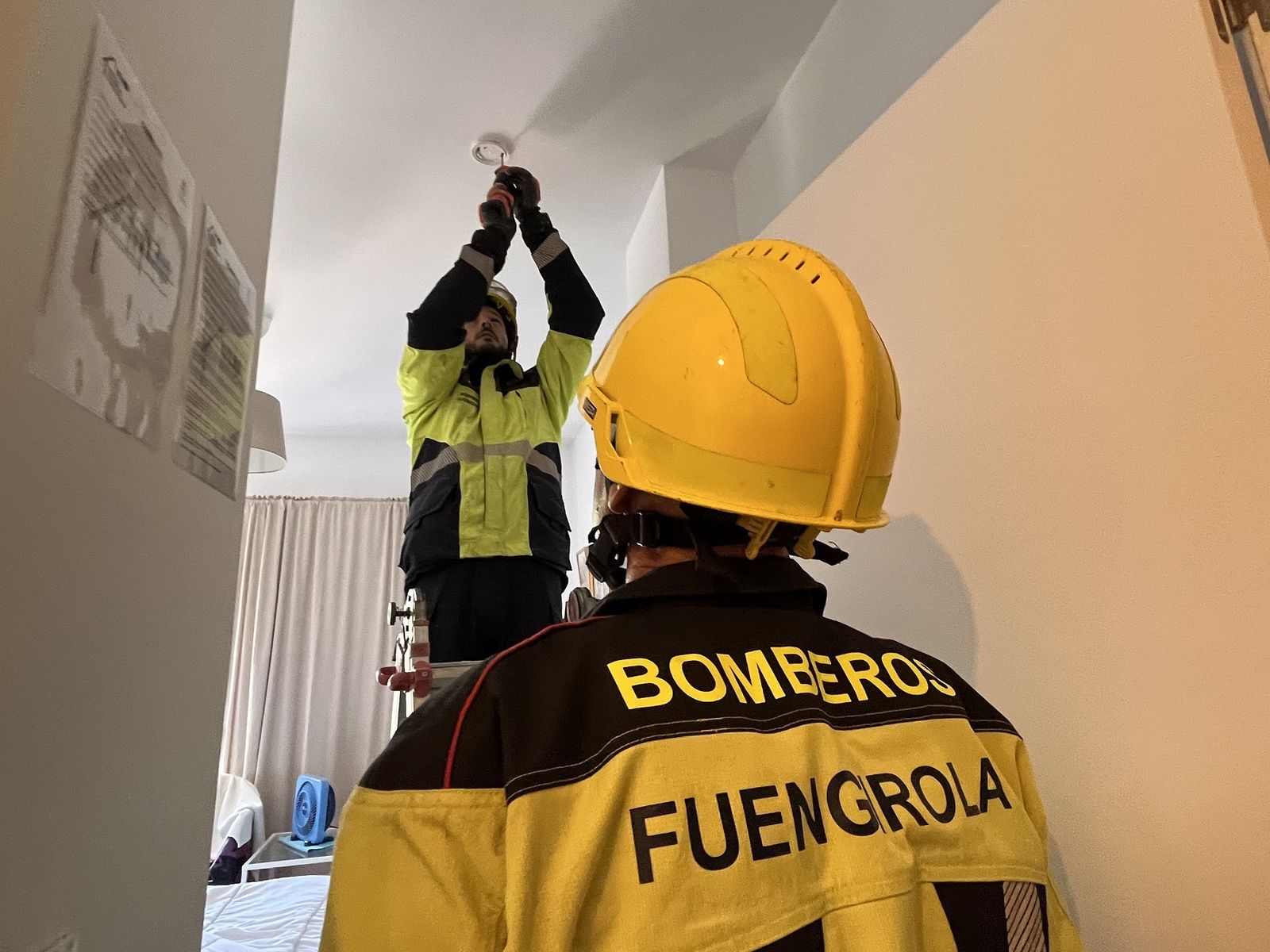 Un bombero instala un detector de humo en una de las viviendas municipales compartidas.