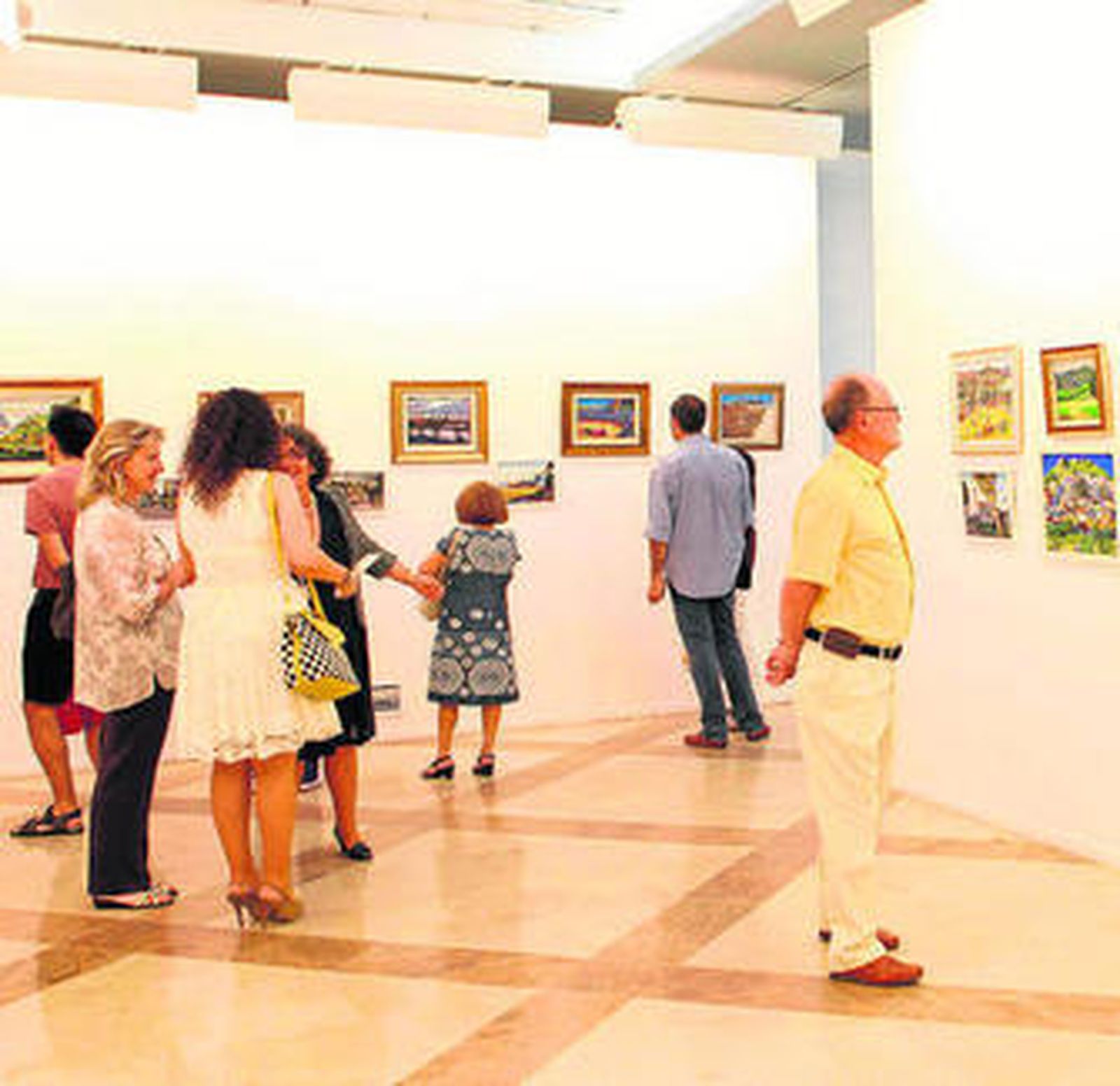 Un grupo de personas mira algunas de las obras expuestas.