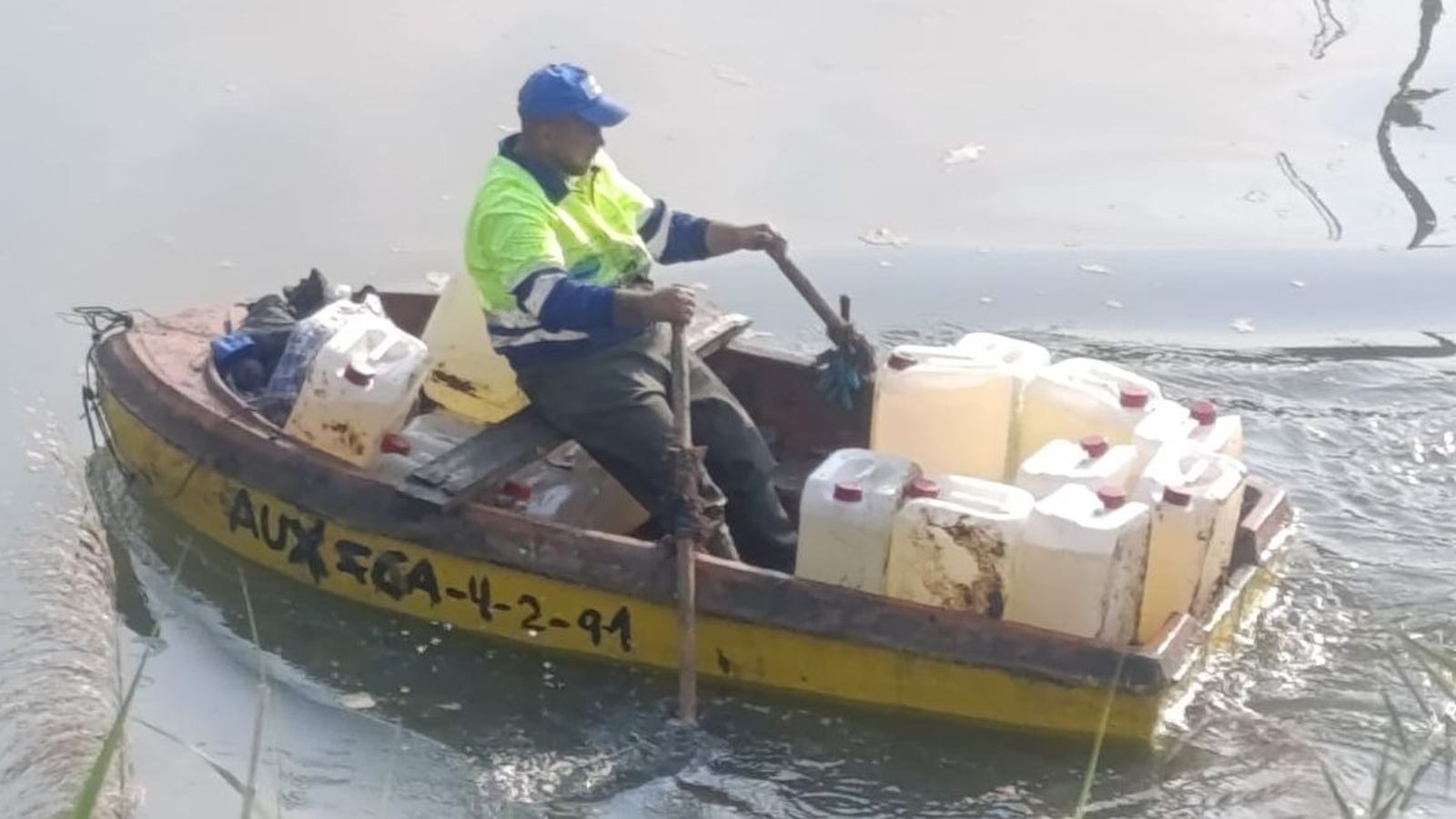 Un operario recoge garrafas del río Iro