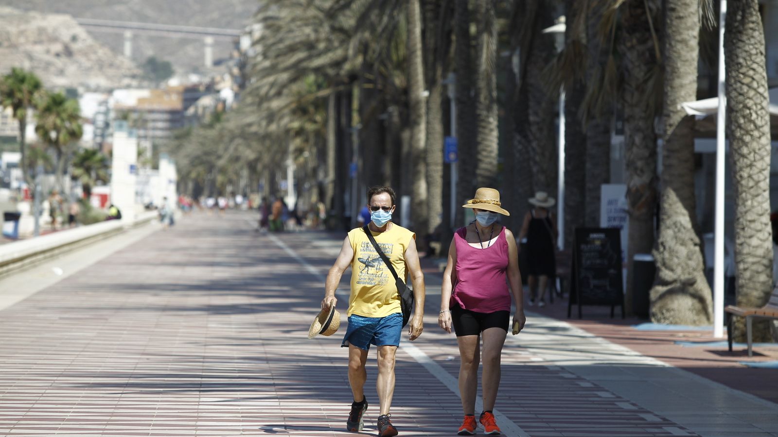 Dos personas caminan por el Paseo Marítimo con sus mascarillas