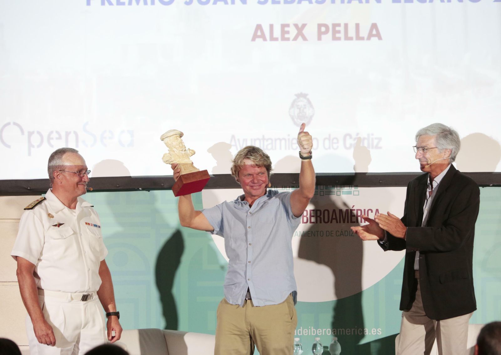 Alex Pella muestra el premio en presencia de Ignacio Horcada y Miguel Ramos.