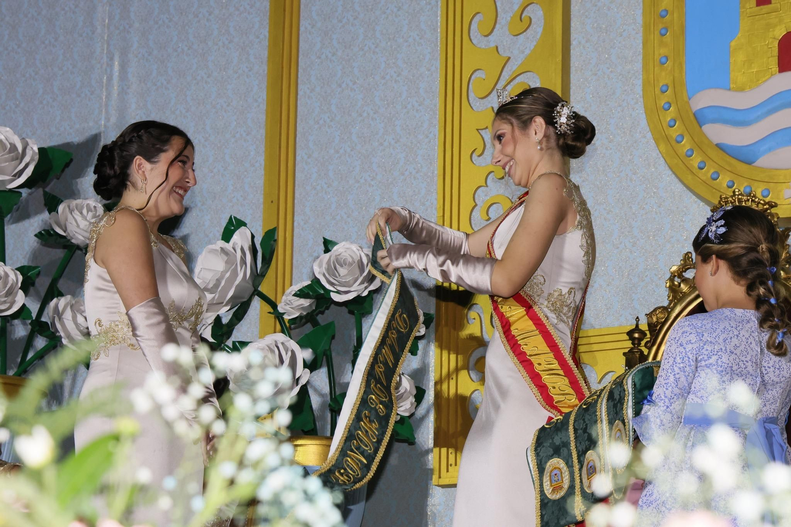 La Dama Mayor entrega la banda a una de las Damas de Honor en la inauguración de las Fiestas Patronales.