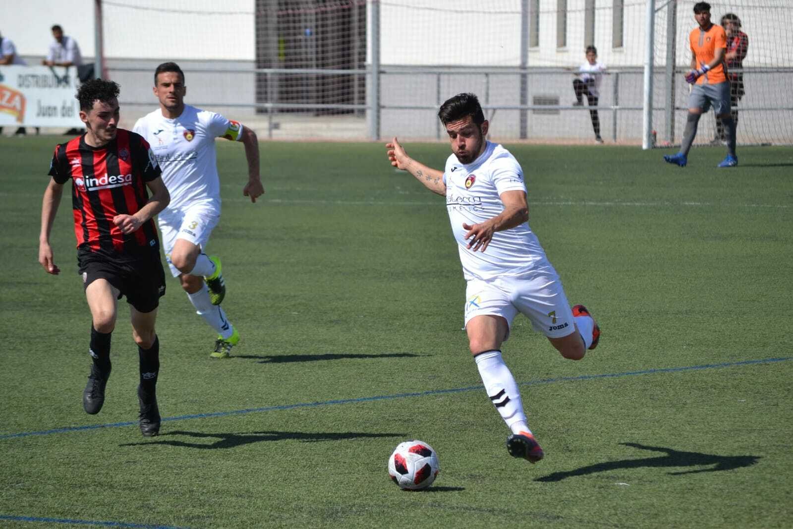 Un jugador del Puente Genil trata de centrar con la oposición de un jugador del Cabecense.