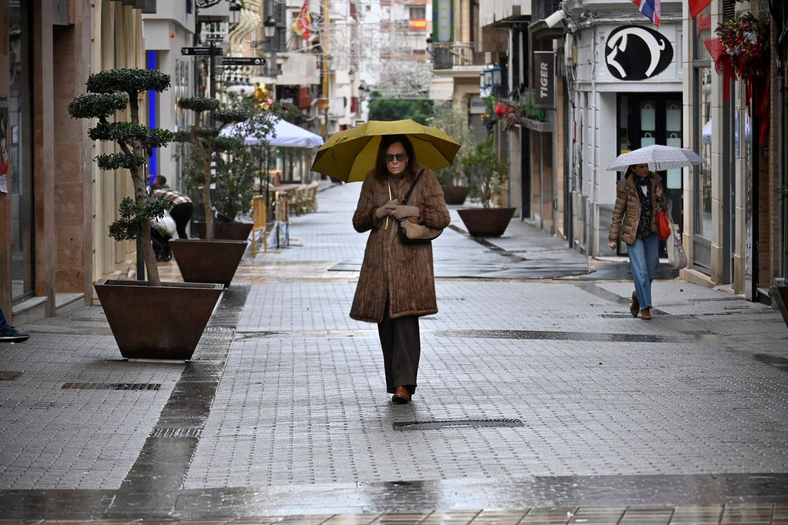 Una mujer se resguarda de la lluvia con un paraguas en las calles del centro de Huelva.