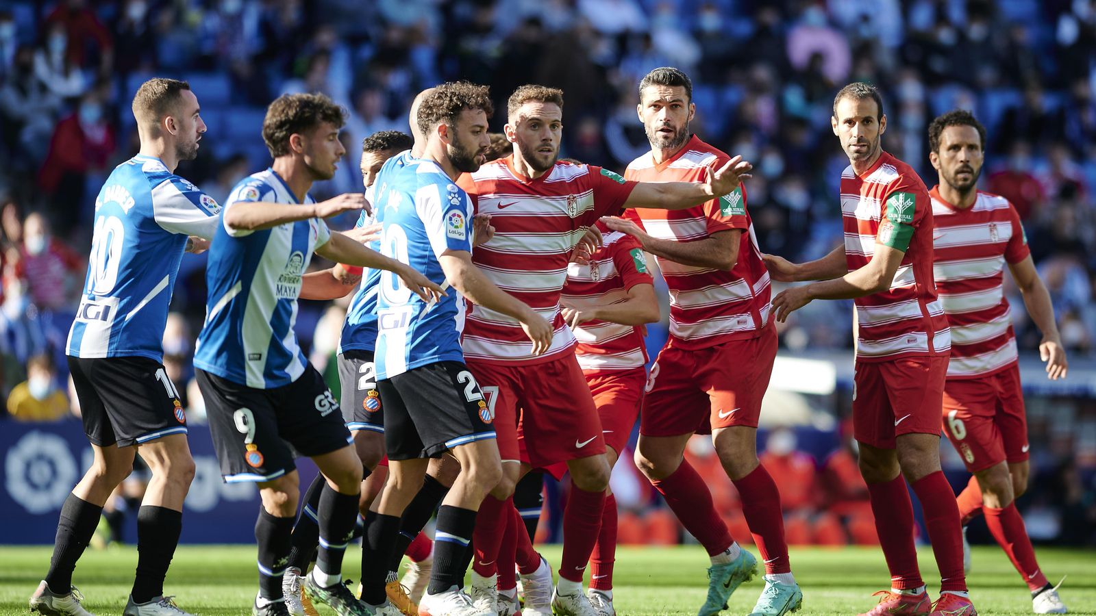 Jugadores de ambos equipos esperan un centro al área