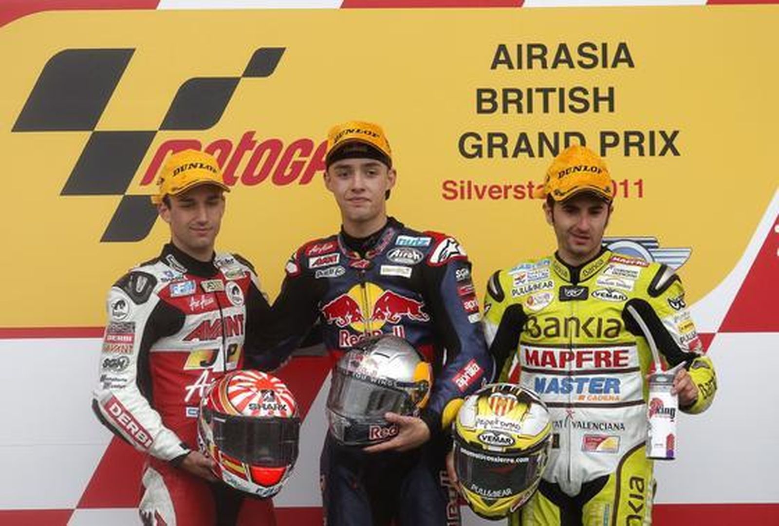 El piloto francés Johann Zarco, segundo; el alemán Jonas Folger, vencedor, y el español Héctor Faubel, tercero, en el podio de 125 cc del Gran Premio de Gran Bretaña.  Foto: EFE