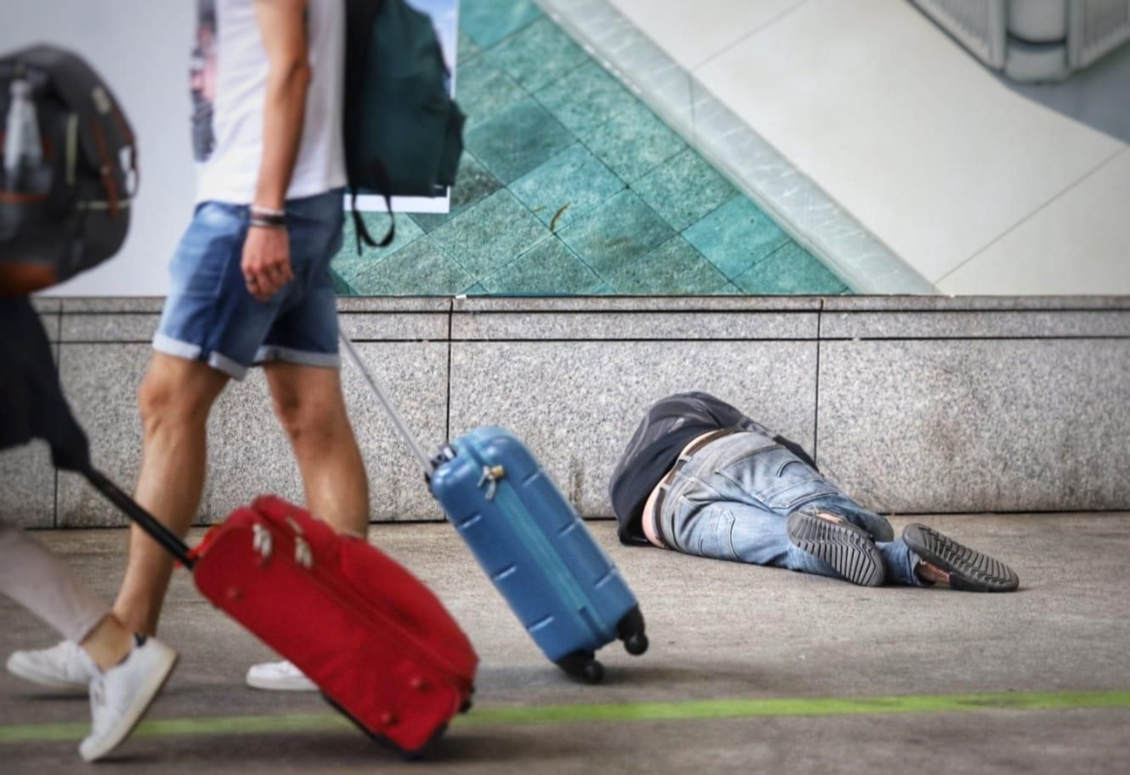 Un sintecho descansa en el suelo del aeropuerto de Málaga.