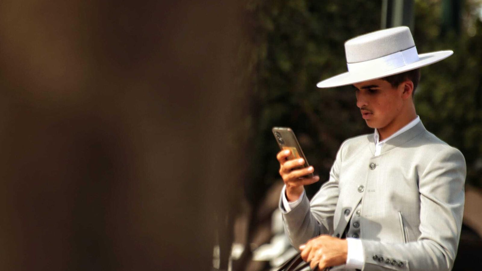 Un joven a caballo, mirando el móvil.