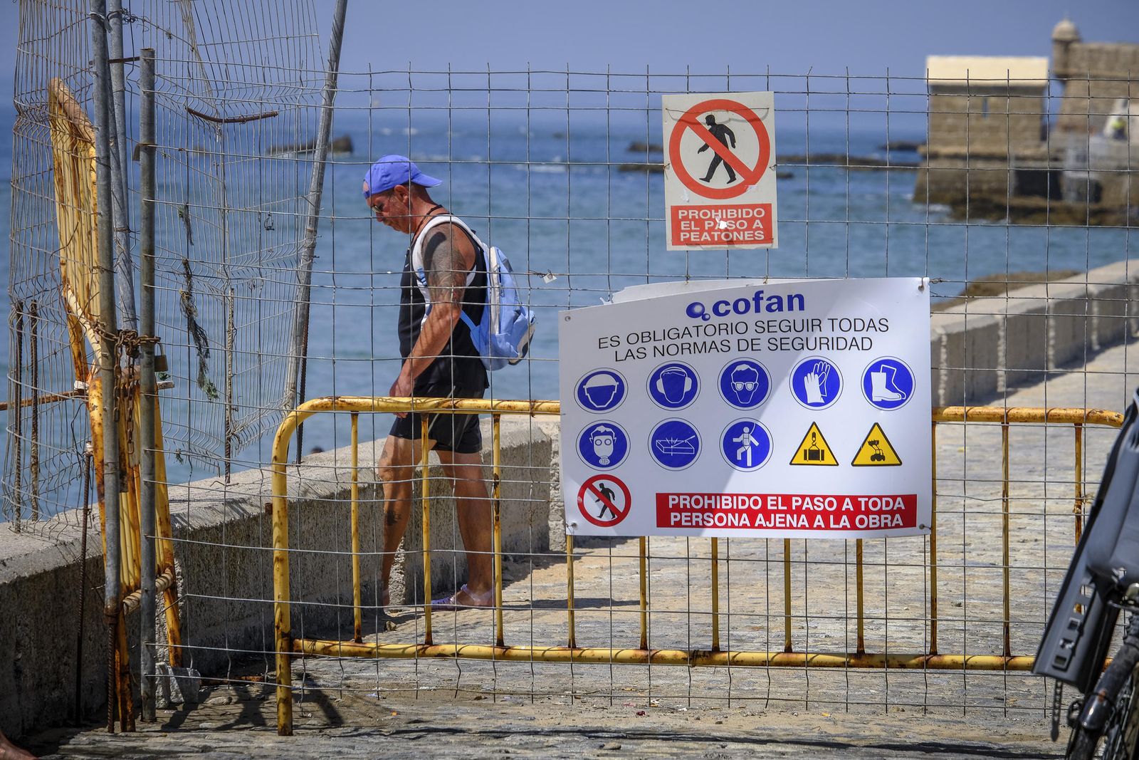 Un hombre accede a la playa de La Caleta detrás de la valla de seguridad de la obra