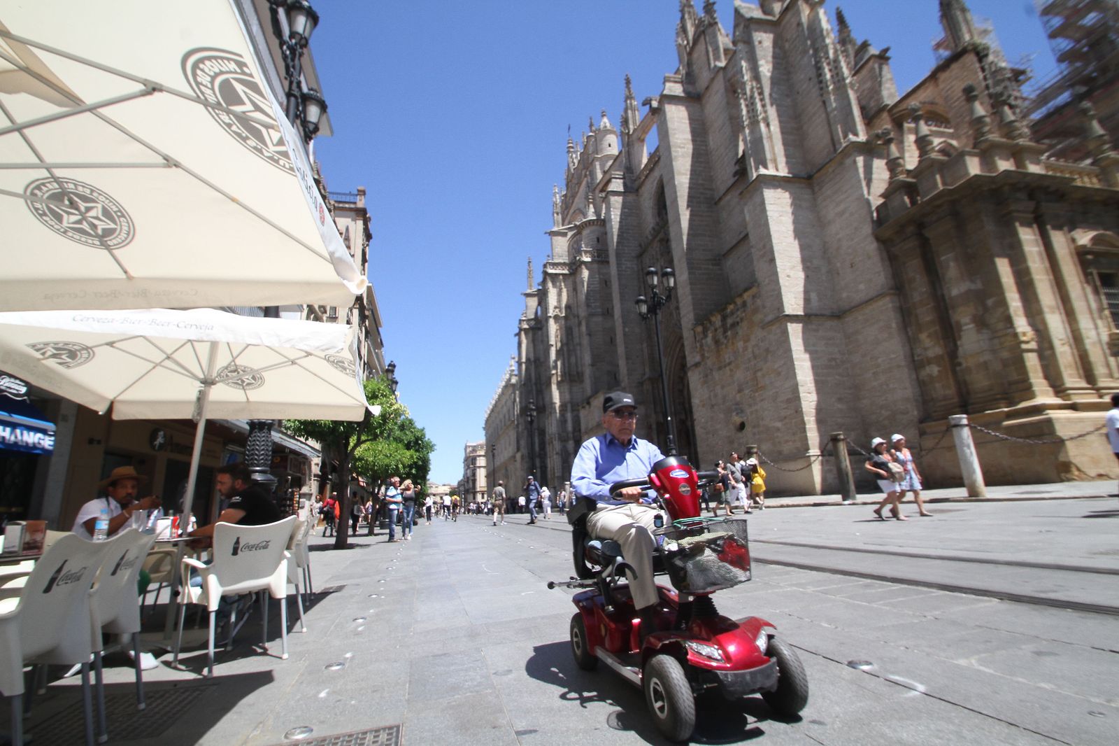Un discapacitado pasa junto a unos veladores de la Avenida de la Constitución.