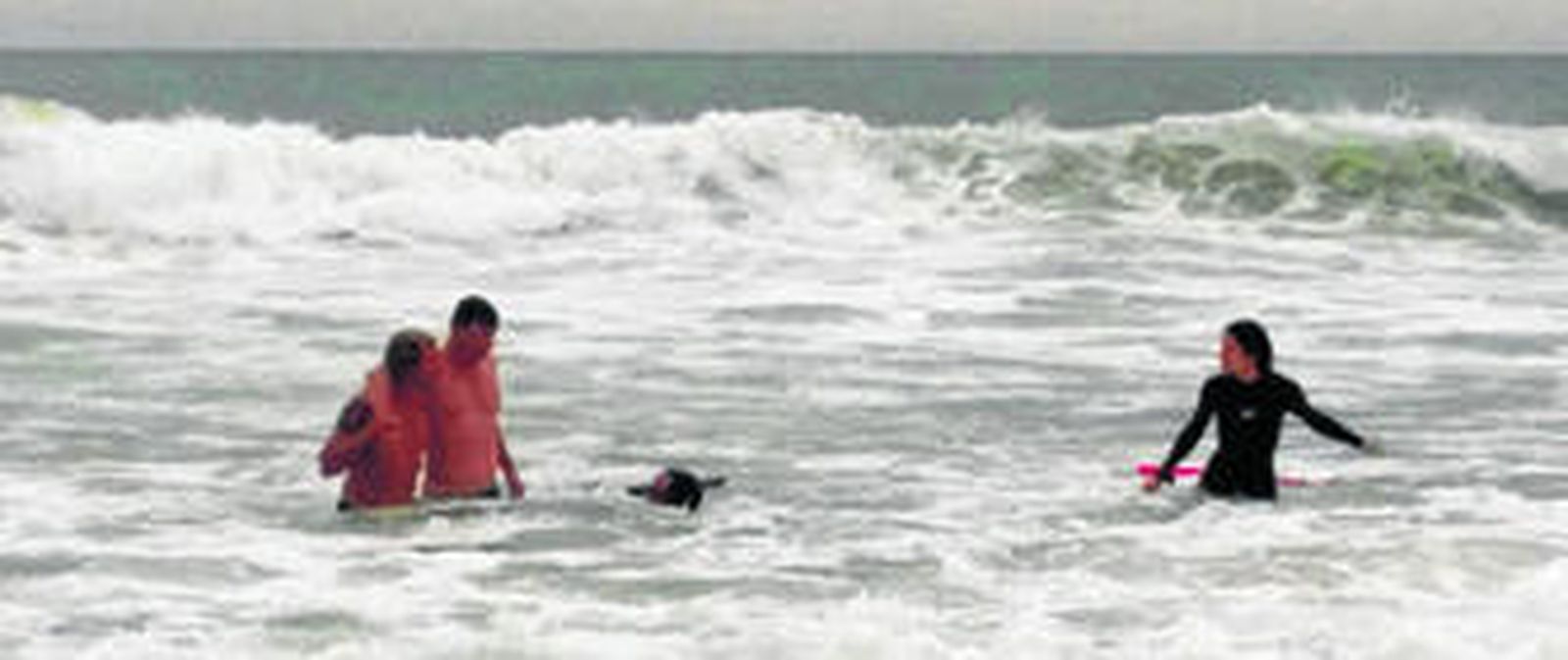 Sergio Manavella conduce hacia la arena a uno de los bañistas rescatados, el pasado domingo en la playa de El Palmar.