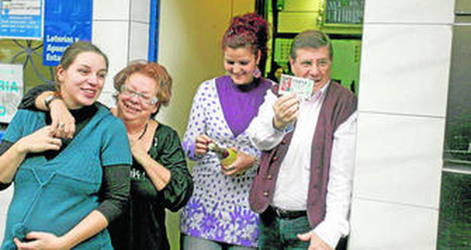 Juan Ángel, el responsable de la administrac¡ión, muestra su décimo de lotería junto a su familia.