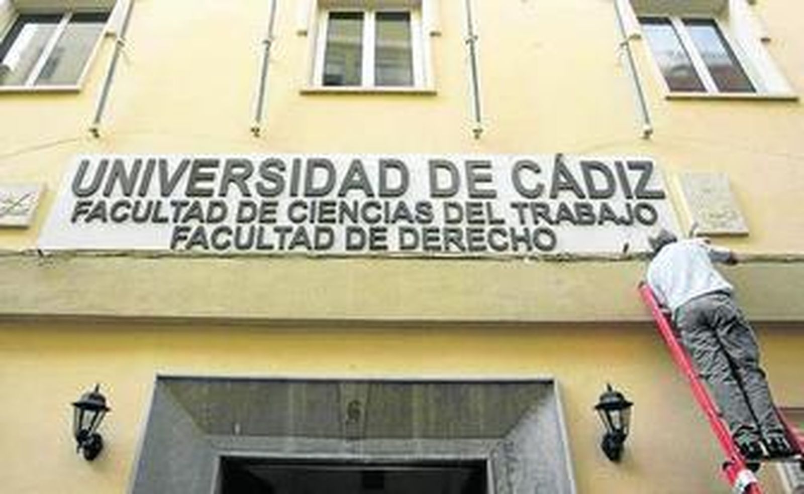 Un operario coloca el cartel de las facultades de la UCA, ayer.