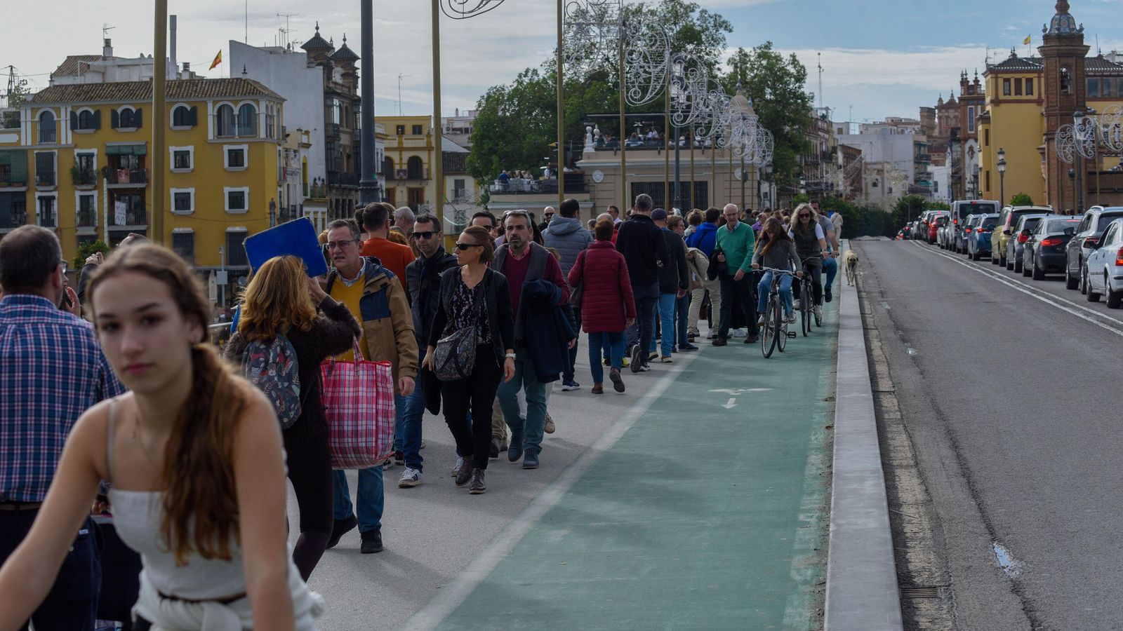 Una masa de gente cruza el puente de Triana.