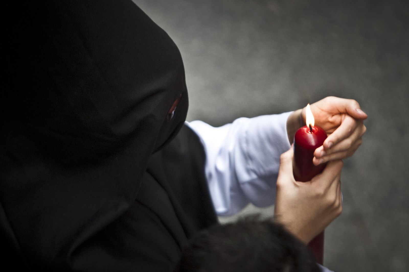 Un penitente protege la llama de su cirio.