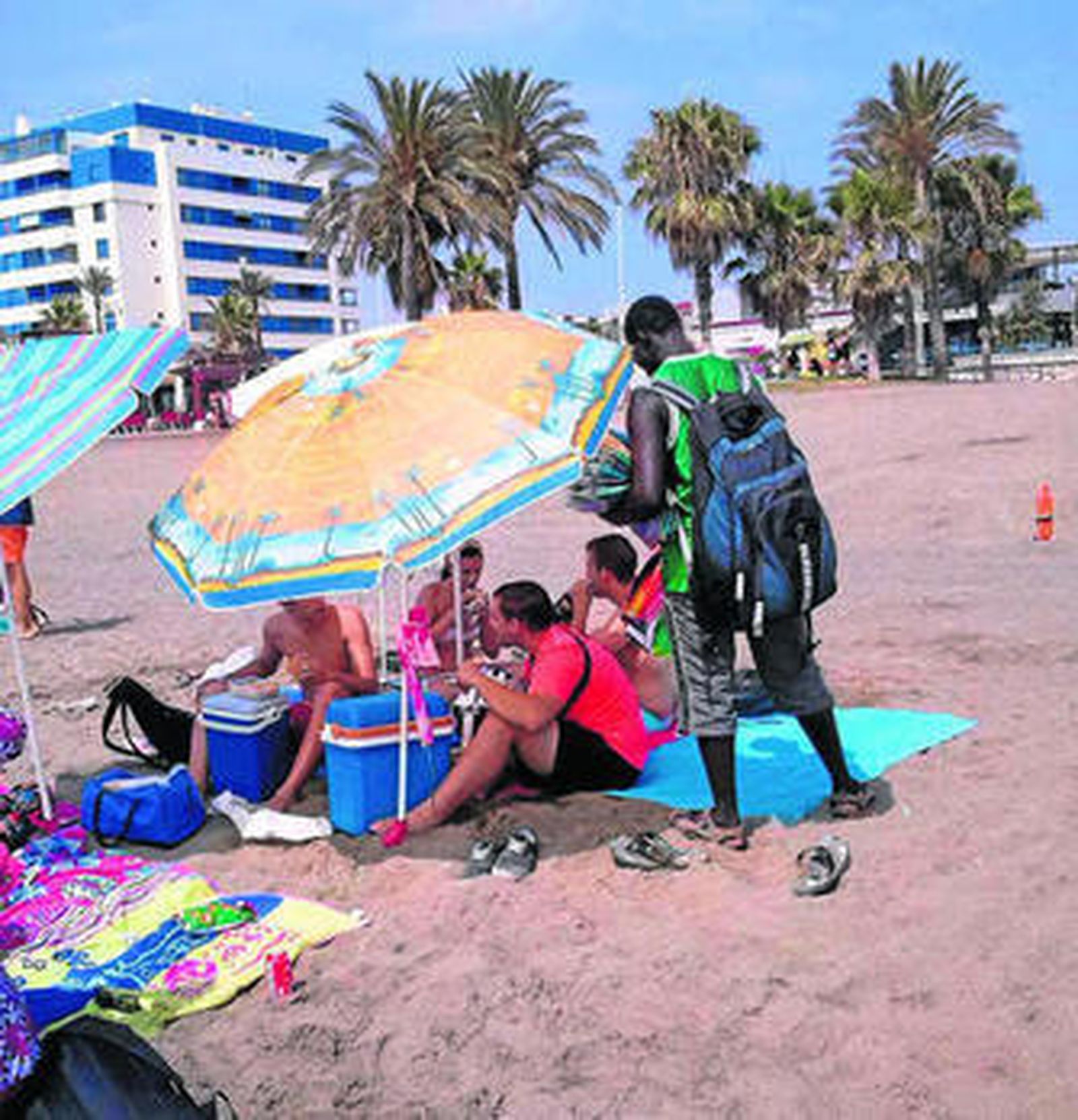 Un vendedor ambulante ofrece prendas de ropa a unas personas.