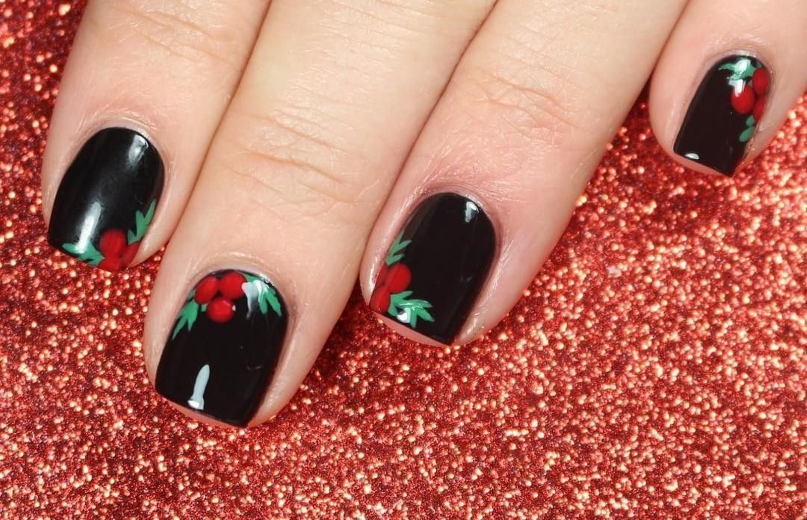 Manicura festiva con motivos navideños sobre negro de @nailstorming